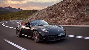 A black Porsche convertible driving on a road