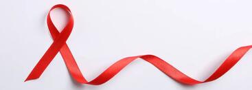 A red ribbon that symbolizes HIV/AIDS awarness. The ribbon is coming untied and trails off to the right.